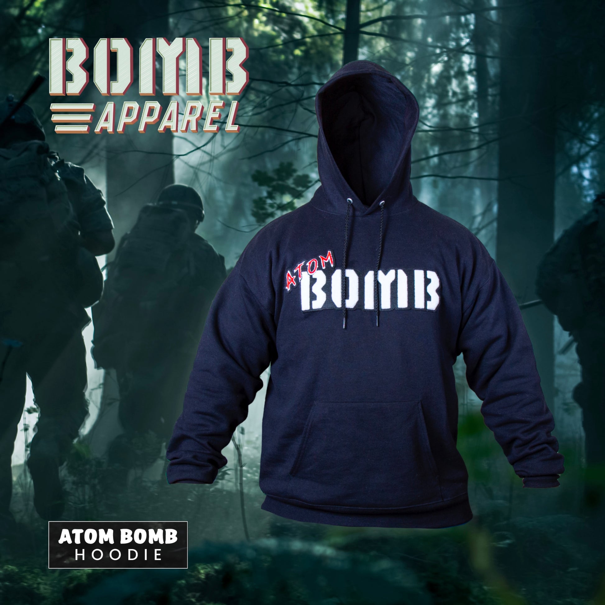 A black fleece hoodie with the Atom Bomb brand logo stitched across the chest, featuring a hood, ribbed cuffs, and a front kangaroo pocket, displayed in a forest setting with a military-themed backdrop.