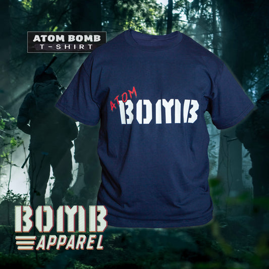 A navy-colored men's t-shirt with the Atom Bomb brand logo printed across the chest, displayed in a forest-like setting with a camouflage pattern in the background.